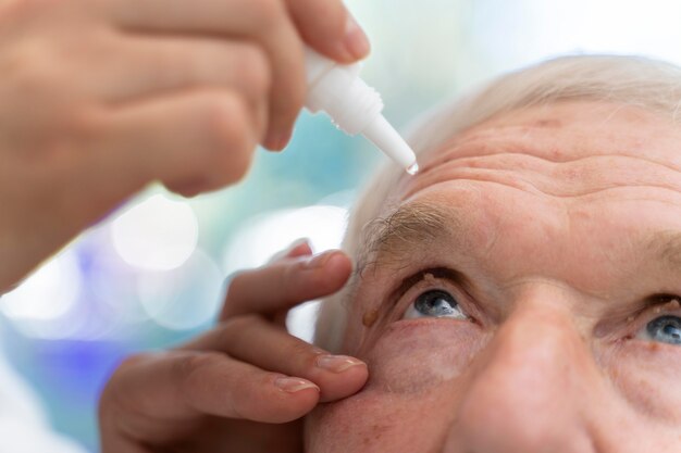 Docteur versant des gouttes pour les yeux pour un patient