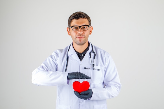 Doctor holding heart en blouse blanche avec stéthoscope et à la recherche positive,
