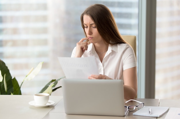 document d&#39;analyse ciblé de femme d&#39;affaires détenant un rapport financier sur le lieu de travail