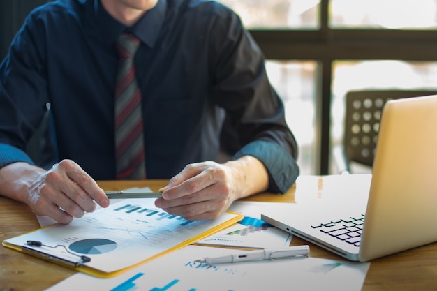 Documents commerciaux sur table de bureau et graphique avec diagramme de réseau social et homme travaillant en arrière-plan.