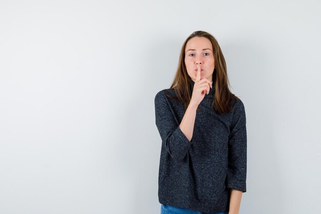 Le doigt de la jeune fille montre le silence sur un fond blanc