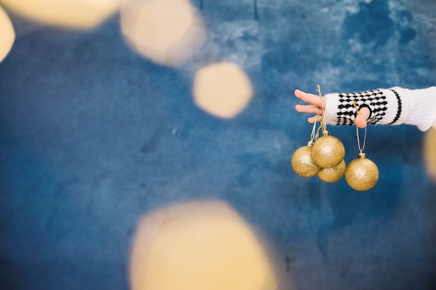 Doigts tenant des boules de Noël dorées