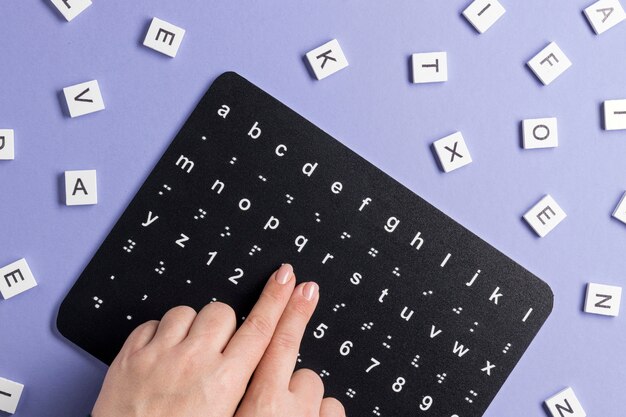 Doigts touchant le tableau de l'alphabet braille