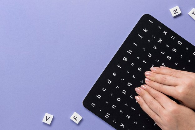 Doigts touchant la vue de dessus du tableau de l'alphabet braille