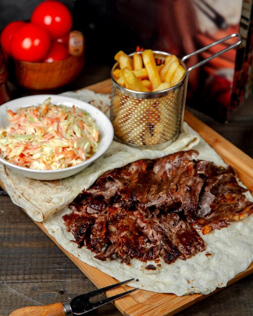 Doner de viande avec frites sur planche de bois