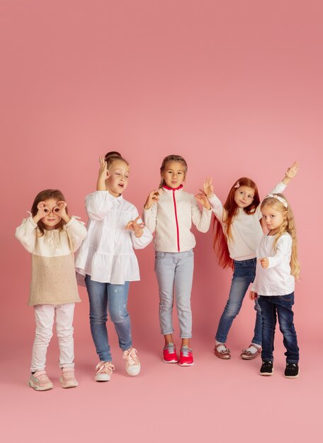 Donner et recevoir des cadeaux pendant les vacances de Noël. Groupe d'enfants souriants heureux s'amusant, célébrant isolé sur fond de studio rose. Rencontre du Nouvel An 2021, enfance, bonheur, émotions.