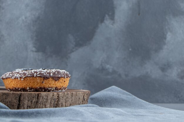 Donut au chocolat sucré sur morceau de bois sur fond de pierre. photo de haute qualité