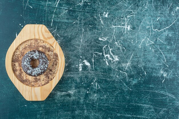 Donut sur une plaque en bois , sur fond bleu. photo de haute qualité