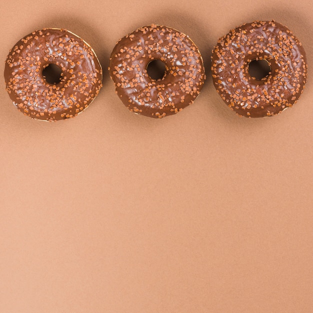 Photo gratuite donuts de glaçage rond sur fond marron