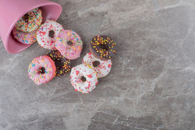 Donuts renversés d'un bol sur une surface en marbre