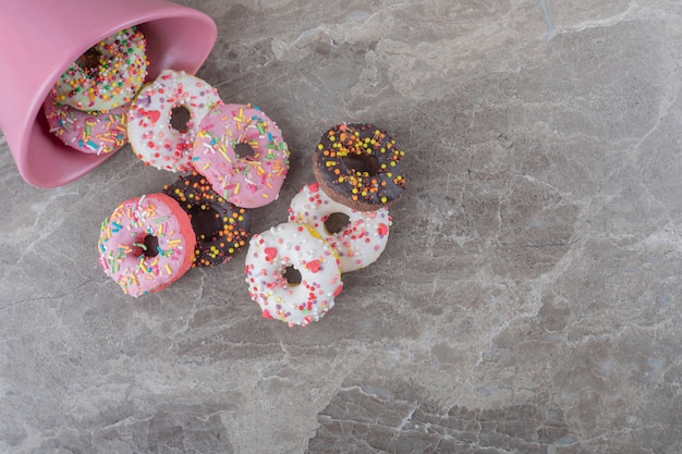 Donuts renversés d'un bol sur une surface en marbre