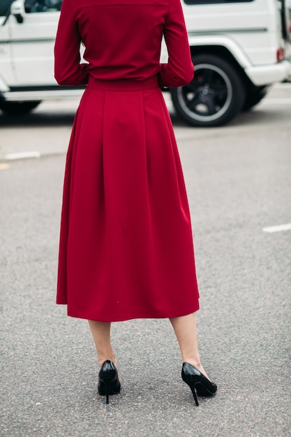 Photo gratuite le dos d'un modèle pose pour la caméra dans une belle robe rouge en tissu dense avec une couture soignée et des boutons blancs