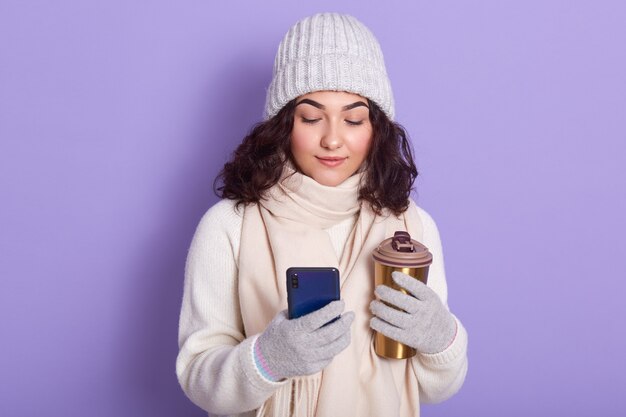 Douce belle jeune femme aux cheveux noirs tenant une tasse thermique