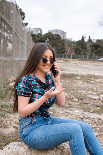 Douce fille assise sur le rocher et riant Photo de haute qualité