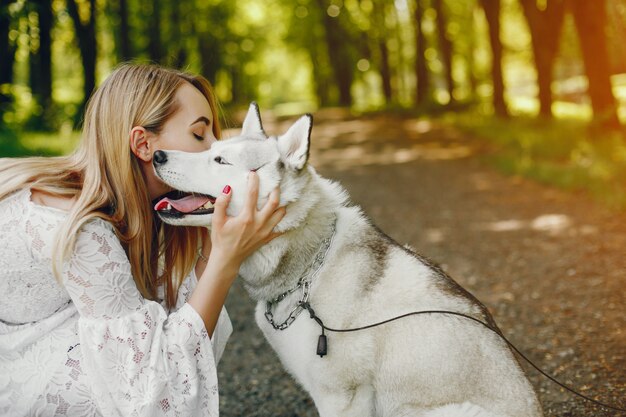 douce fille aux cheveux clairs vêtue de robe blanche joue avec son chien