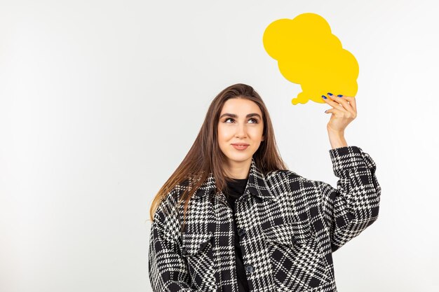 Douce jeune femme tenant une boîte parlante et debout fond blanc