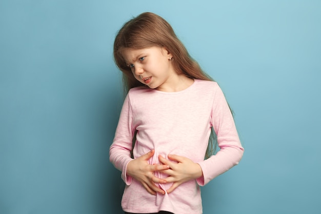 douleur abdominale. triste adolescente avec des douleurs abdominales sur bleu. Concept d'expressions faciales et d'émotions de personnes