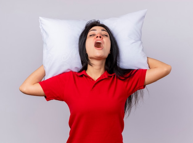 Douleur jeune femme malade tenant un oreiller sous la tête avec les yeux fermés isolé sur un mur blanc