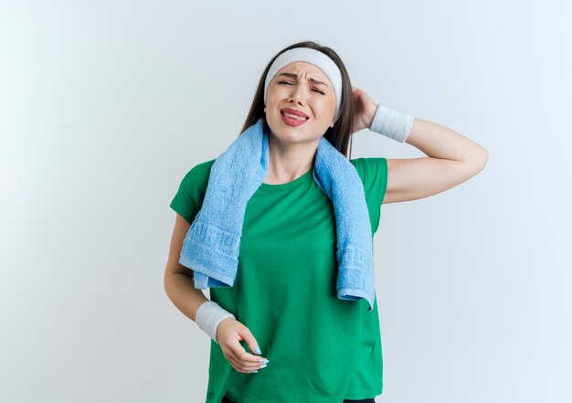 Douleur jeune femme sportive portant un bandeau et des bracelets avec une serviette autour du cou à garder la main derrière la tête