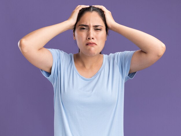 Douleur jeune fille caucasienne brune met les mains sur la tête sur le violet