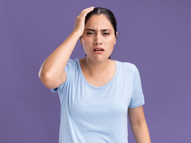 Douleur jeune fille caucasienne brune mettant la main sur la tête sur violet