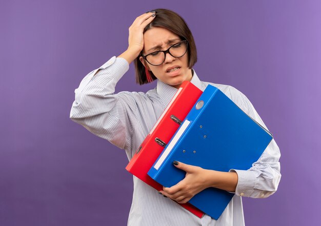 Douleur jeune fille de centre d'appels portant des lunettes tenant des dossiers mettant la main sur la tête avec les yeux fermés souffrant de maux de tête isolés sur violet