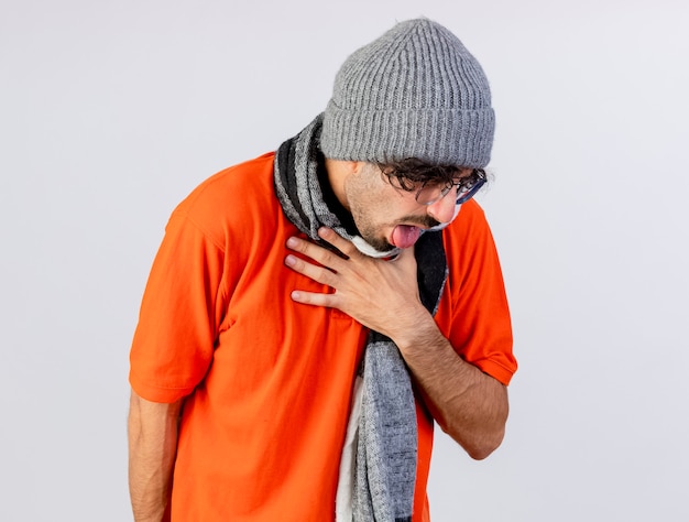 Douleur jeune homme malade portant des lunettes chapeau d'hiver et écharpe tenant la toux de la gorge isolé sur un mur blanc