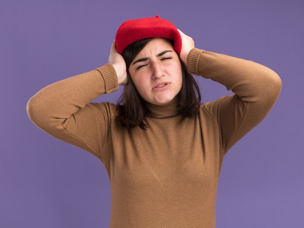 Douleur jeune jolie fille caucasienne avec chapeau de béret tenant la tête