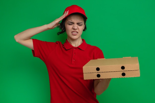 Photo gratuite douleur jeune jolie livreuse tenant des boîtes à pizza et mettant la main sur sa tête