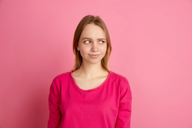 Doute, incertitude. Portrait de jeune femme caucasienne sur studio rose