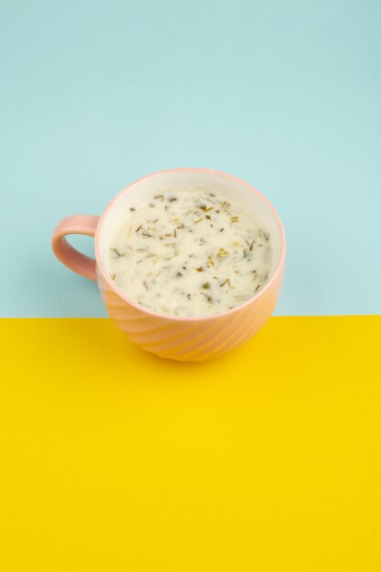 Dovga savoureux repas traditionnel à l'intérieur de la tasse rose et contenant des herbes vertes sur le bleu et le jaune