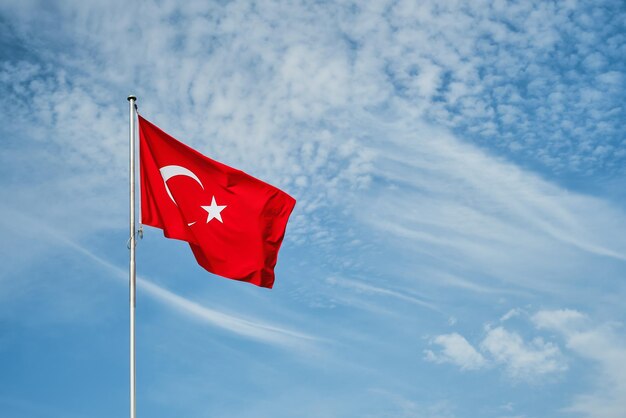 Le drapeau turc flotte sur un mât contre un ciel avec des nuages avec espace de copie Idée pour le fond ou le papier peint