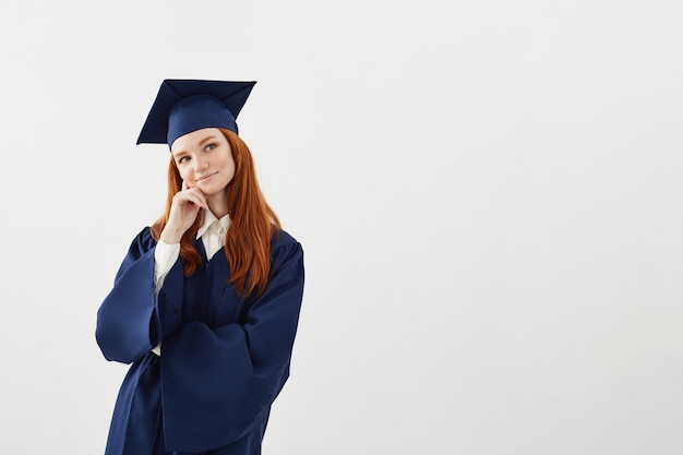 Dreamy belle femme diplômé pensant rêver sur une surface blanche