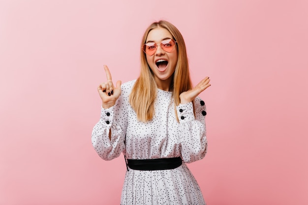 Drôle de femme caucasienne en robe blanche à la mode bénéficiant de portraitshoot. Bonne femme positive aux cheveux raides en riant.