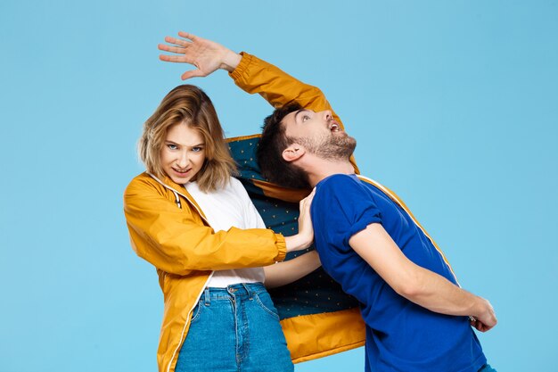 Drôle jeune beau couple portant une veste sur un mur bleu