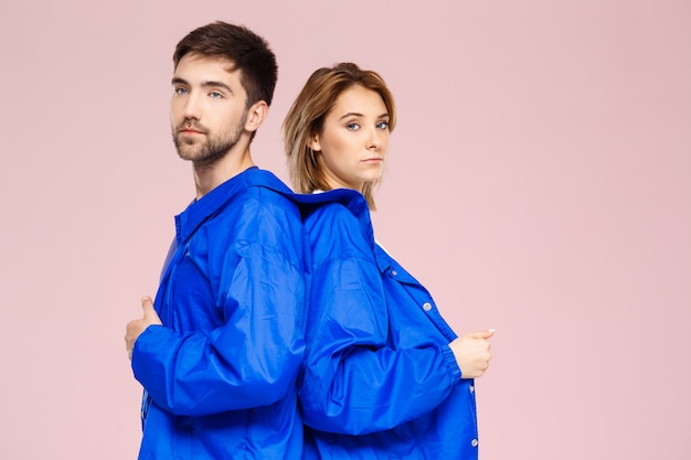 Drôle jeune beau couple portant une veste sur un mur rose clair