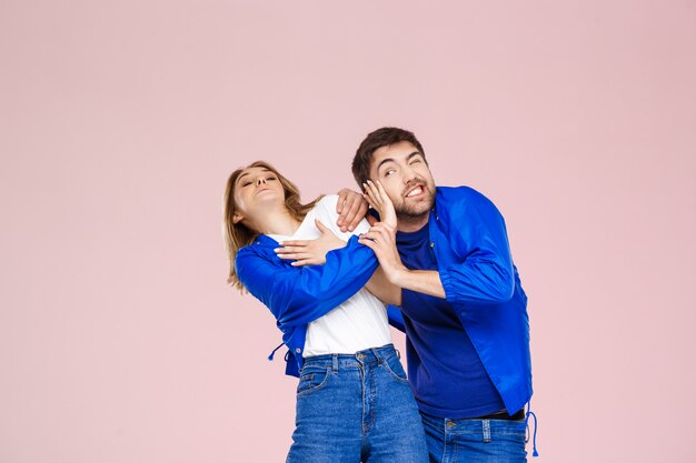 Drôle jeune beau couple portant une veste sur un mur rose clair