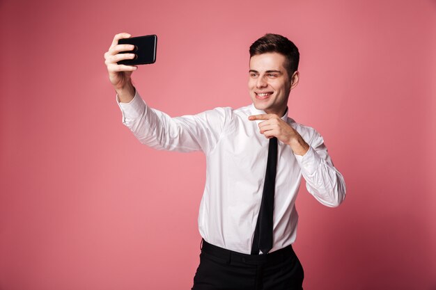 Drôle jeune homme d'affaires faire selfie par téléphone mobile