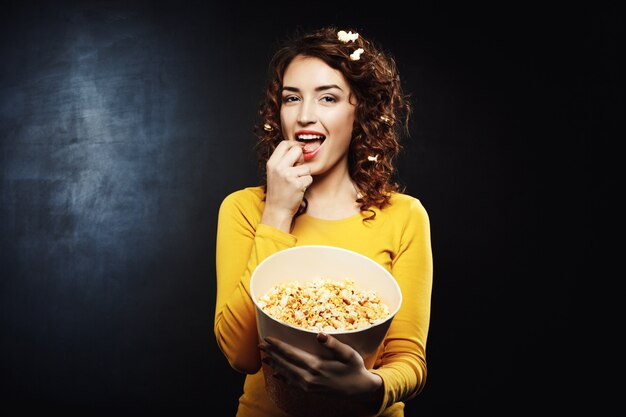 Drôle jolie femme mangeant du pop-corn sucré salé savoureux au cinéma