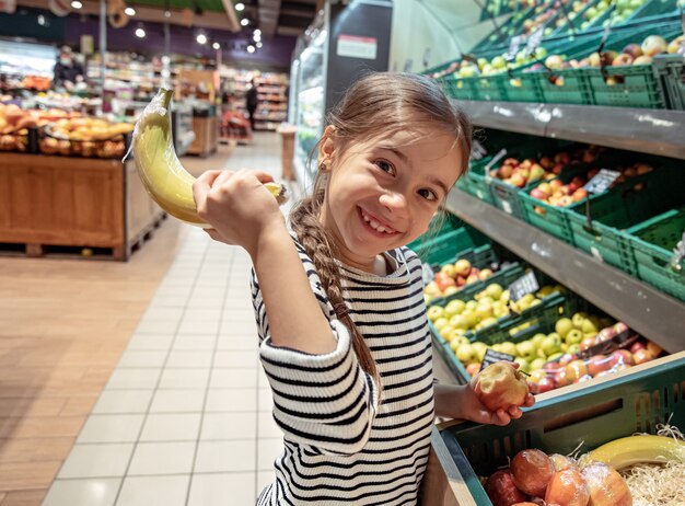 Drôle de petite fille à la banane au supermarché.