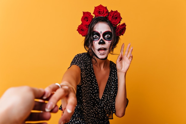 Drôle de zombie mexicain choqué posant sur fond jaune. Modèle féminin inspiré en tenue d'halloween exprimant la stupéfaction.