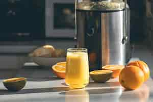 Photo gratuite du jus d'orange frais dans un verre près de la table de la cuisine