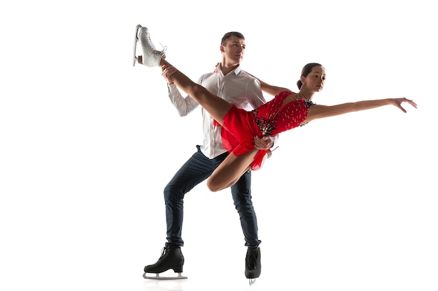 Duo de patinage artistique isolé sur un mur de studio blanc avec fond. Deux sportifs pratiquant et s'entraînant dans l'action et le mouvement. Plein de grâce et en apesanteur. Concept de mouvement, sport, beauté.