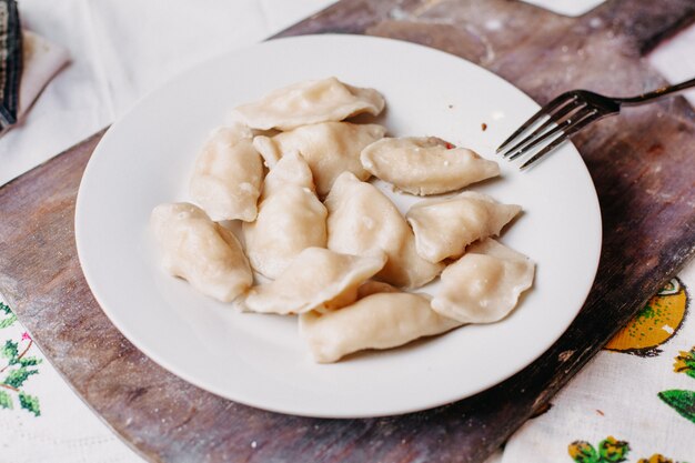 Dushpere célèbre repas oriental avec de la pâte à l'intérieur de la viande hachée salée poivrée à l'intérieur de la plaque blanche