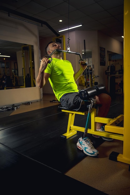 Photo gratuite dynamique. homme handicapé s'entraînant dans la salle de gym du centre de rééducation, pratiquant. homme actif avec handicap. concept de mode de vie sain et actif, motivation, concentration, inclusion et diversité.