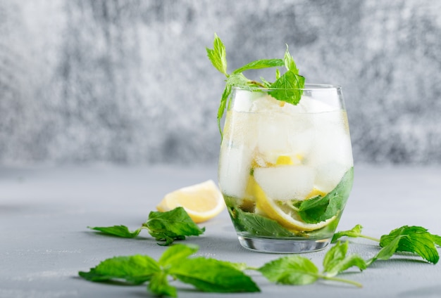 Eau de désintoxication glacée au citron et à la menthe dans un verre sur une surface grise et grunge