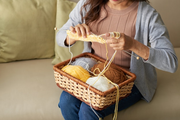 Photo gratuite Écharpe tricotée femme d'âge mûr méconnaissable, assis sur le canapé à la maison