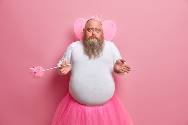 Photo gratuite un échec masculin douteux sans aucune idée se demande pourquoi ses capacités ont disparu, joue dans des performances pour enfants, porte un costume spécial, tient une baguette magique