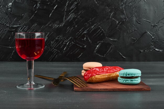 Eclair à la fraise avec macarons français et un verre de vin.