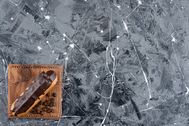 Eclair sucré au chocolat glacé placé sur fond de marbre.